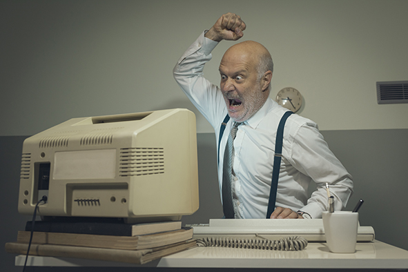 Angry office worker hitting his outdated computer