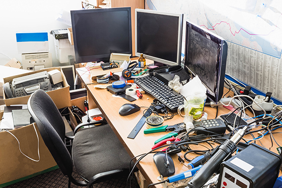 A messy desk with cables and rubbish everywhere.