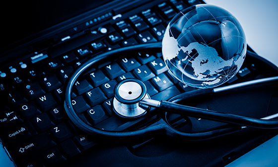 Glass globe and stethoscope placed on top of a laptop.