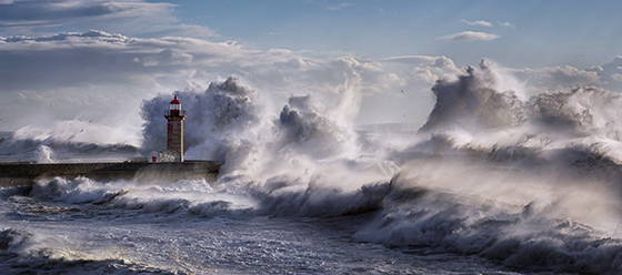 Giant waves incoming towards a lighthouse.