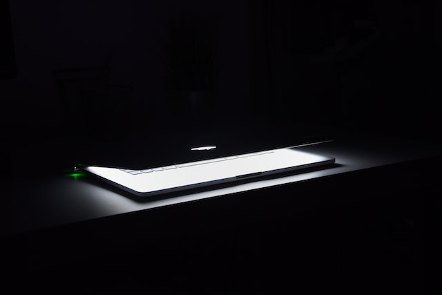 Apple laptop on in a dark room.